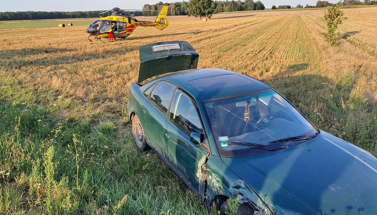 uszkodzony samochód marki Audi, stojący na polu śmigłowiec LPR