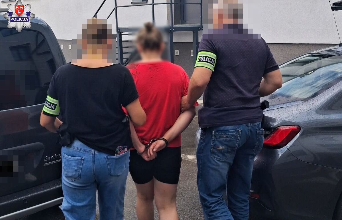 nieumundurowani policjanci prowadzą podejrzaną, w tle samochody i ściana budynku