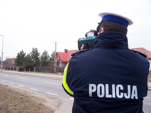 zdjęcie ilustracyjne - policjant z radarowym miernikiem prędkości