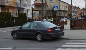 Stojący na jezdni samochód marki Volvo i oparty o ogrodzenie rower uczestniczący w wypadku.