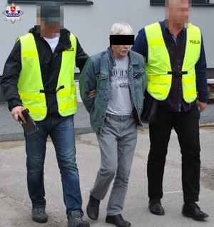zatrzymany za znęcanie nad żoną 54-latek doprowadzany przez dwóch policjantów