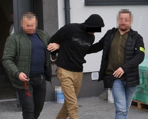 zatrzymany prowadzony przez policjantów służby kryminalnej