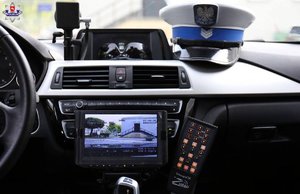 zdjęcie ilustracyjne - wnętrze radiowozu z wideo rejestratorem i czapką policjanta Wydziału Ruchu Drogowego