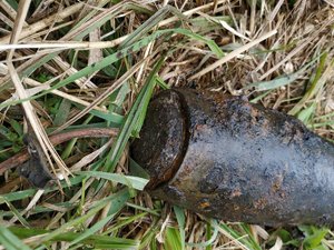 leżący w trawie skorodowany pocisk przeciwlotniczy