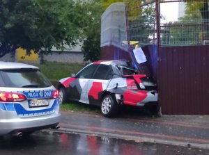 uszkodzony samochód marki Honda stojący przy metalowej wiacie, obok policyjny radiowóz