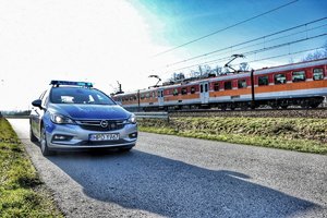 radiowóz na jezdni, w tle pociąg