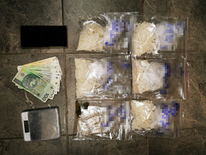 leżące na podłodze zabezpieczone narkotyki, smartfon, pieniądze i waga