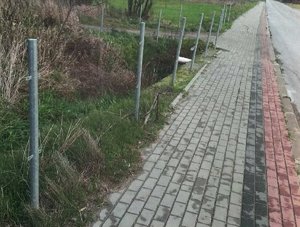 metalowe słupki bariery drogowej, zamontowane na trawiastym poboczu rogi