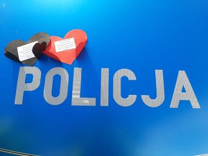 pokrywa silnika radiowozu z napisem Policja oraz papierowe czerwone i czarne serduszka.