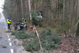 policjanci na miejscu wypadku, leśne drzewa, uszkodzony samochód marki Skoda