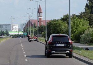 stojące na jezdni samochód marki Volvo i motocykl marki BMW, w tle budynki i kościół