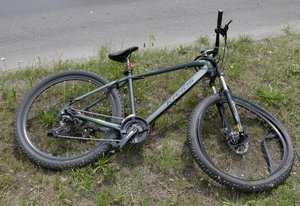 uszkodzony rower leżący na trawiastym poboczu