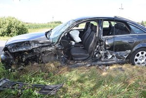 stojący częściowo na poboczu uszkodzony samochód marki Audi