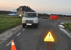 oznakowane miejsce wypadku drogowego, stojący na jezdni samochód marki Volkswagen, stojący na jezdni czerwony parawan z napisem Straż, w tle policjanci