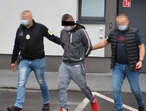 nieumundurowani policjanci prowadzą podejrzanego