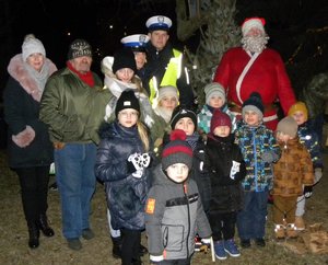 policjanci Wydziału Ruchu Drogowego stojący przy choince, obok  dorośli,dzieci i Święty Mikołaj