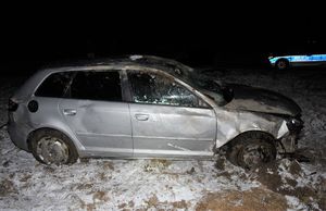 stojący na polu uszkodzony samochód marki audi, w tle radiowóz