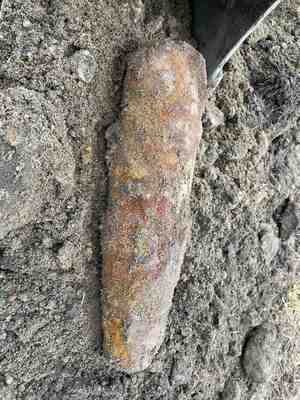 leżący na gruntowym podłożu skorodowany pocisk artyleryjski