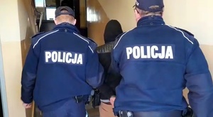 policjanci prowadzą po schodach zatrzymanego mężczyznę