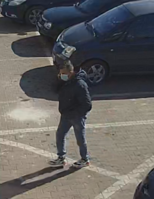 mężczyzna w granatowej kurtce na parkingu samochodowym