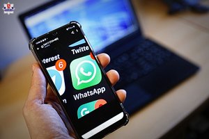 trzymany w ręku smartfon, w tle laptop