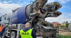 ciężarowy samochód z pompą do betonu, obok policjant