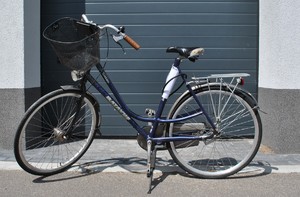 stojący przy drzwiach garażowych granatowy rower typu damka, marki Batavus