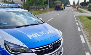 miejsce wypadku drogowego, stojący na drodze radiowóz, samochód ciężarowy marki Man, obok policjant