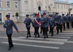policjanci i poczet sztandarowy przechodzą przez ulicę