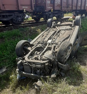 uszkodzony samochód marki Opel Astra w tle wagony pociągu towarowego