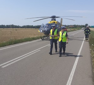idący po jezdni policjanci, w tle śmigłowiec LPR