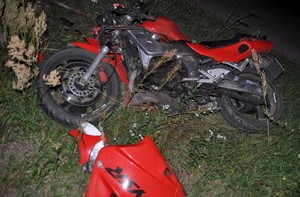 leżący na trawiastym podłożu uszkodzony motocykl