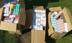 stojące na trawiastym podłożu pudełka z paczkami papierosów