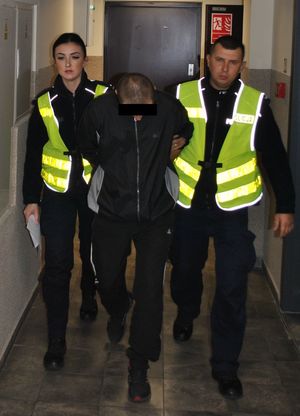 policjanci prowadzą tymczasowo aresztowanego
