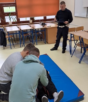 uczniowie w konkurencji pomocy przedmedycznej, w tle policjant