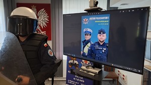 uczeń ze sprzętem policyjnym, w tle ekran monitora