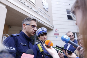 policjant i policjantka, w tle budynek szkoły