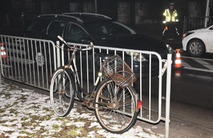 miejsce wypadku drogowego, stojący przy barierkach rower, stojący na jezdni samochód, w tle policjant drogówki