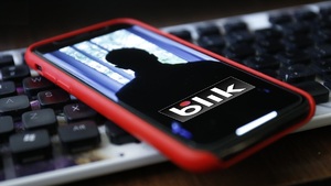 smartfon z napisem BLIK na ekranie, w tle klawiatura komputerowa