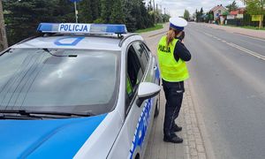 radiowóz i policjantka z miernikiem prędkości