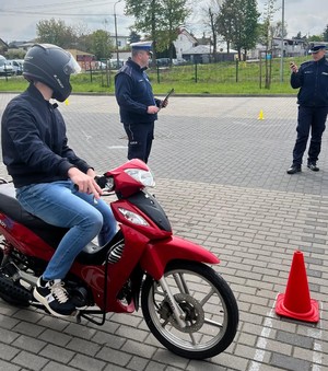 uczeń na motorowerze w tle policjanci