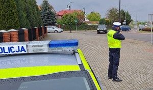 pojazdy na drodze i policjant z miernikiem prędkości