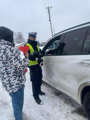 samochód, policjant i dziecko z papierowym czerwonym sercem