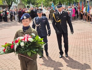 kadet z wiązanką, z tyłu Komendant Powiatowy Policji w Łukowie i Komendant Powiatowy Państwowej Straży Pożarnej w Łukowie