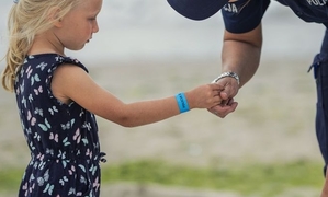 dziewczynka sukience trzyma rękę policjanta