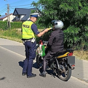 policjant sprawdza stan rzeźwości kierującego motorowerem