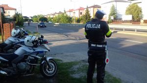 policyjne motocykle na drodze, stojący na chodniku policjant ruchu drogowego, samochód jadący po jezdni