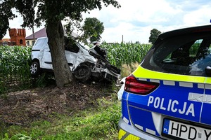 radiowóz i stojący przy drzewie uszkodzony samochód Ford Transit