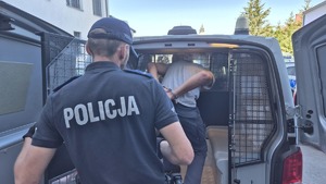 policjant umieszcza zatrzymanego mężczyznę w radiowozie