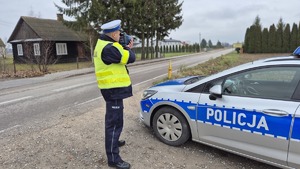 policjant drogówki z miernikiem prędkości, obok radiowóz